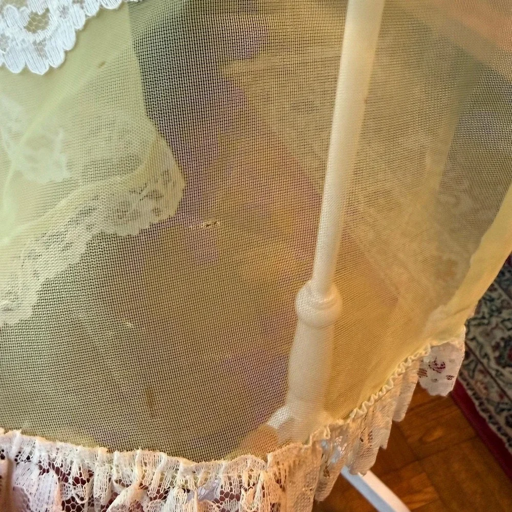 Vintage sheer yellow apron with ornate white lace trim and a bow-accented pocket